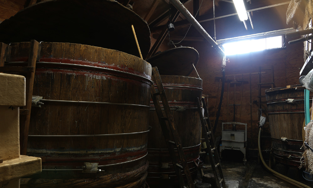 本社にある酢蔵の写真。木製の大きな樽が特徴的。